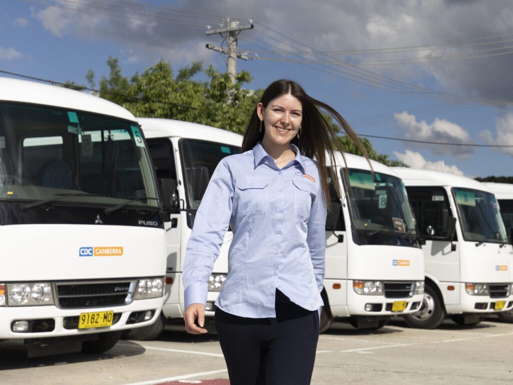Employee smiling next to buses