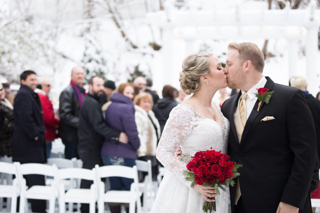 Young Bride And Groom Kiss In Front Of Guests At Winter Wedding