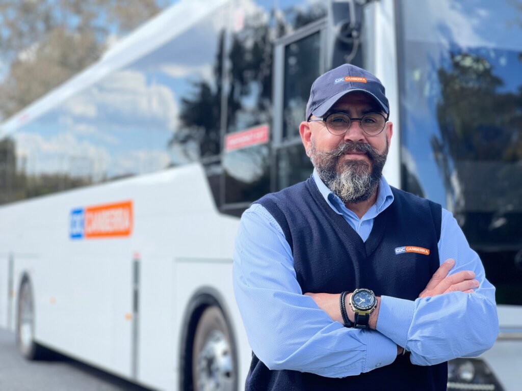 employee posing in front of bus