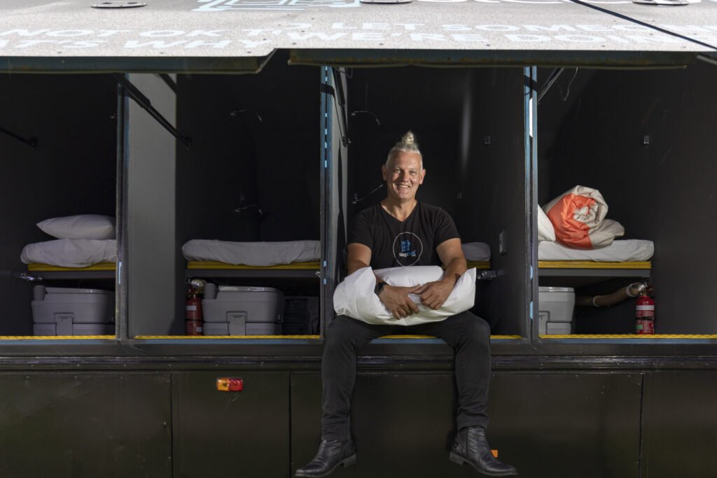 Sleep bus image of employee sitting in front of sleep bus